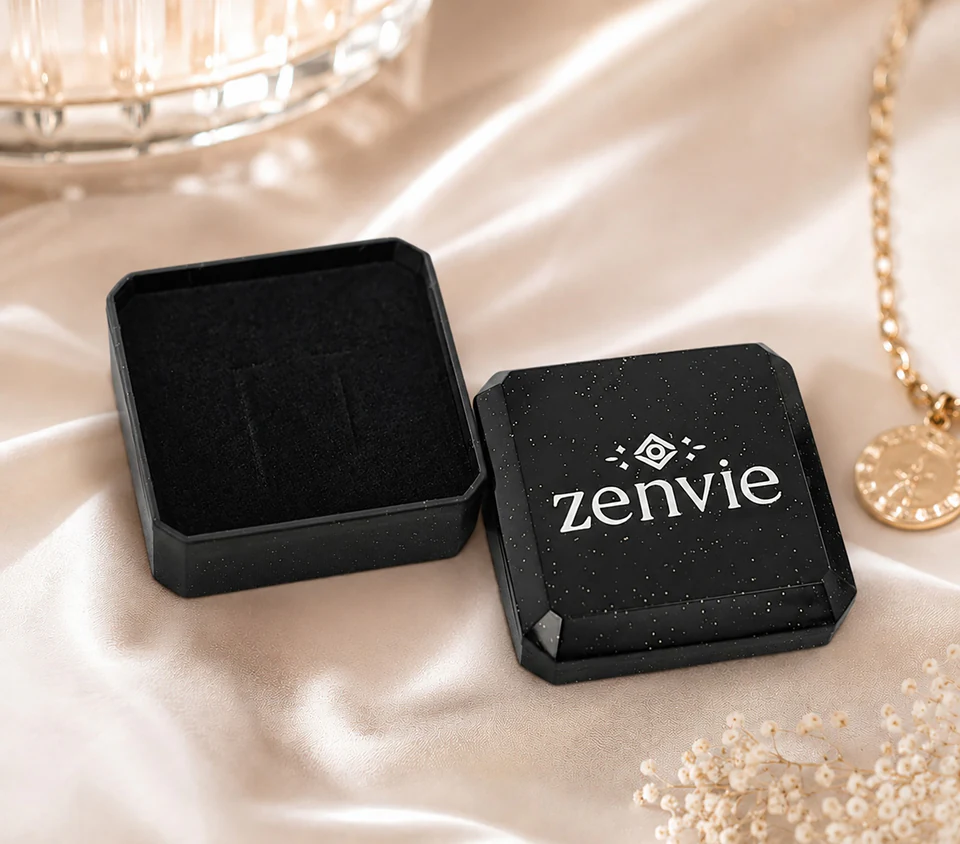 An open black Zenvie gift box on softly lit champagne fabric